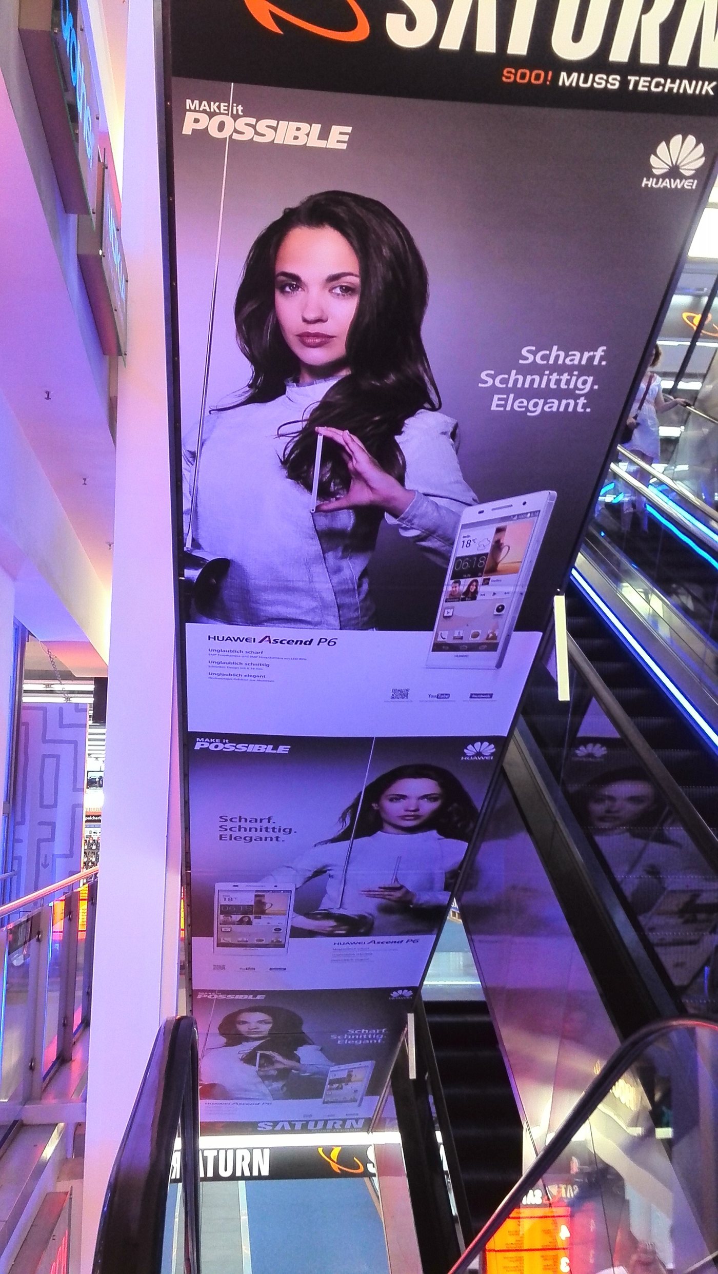 Langformatige Huawei-Ascend-P6-Plakate über einer Rolltreppe bei Saturn