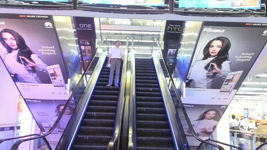 Großflächenwerbung für das Huawei Ascend P6 an Rolltreppen in einem Saturn-Markt